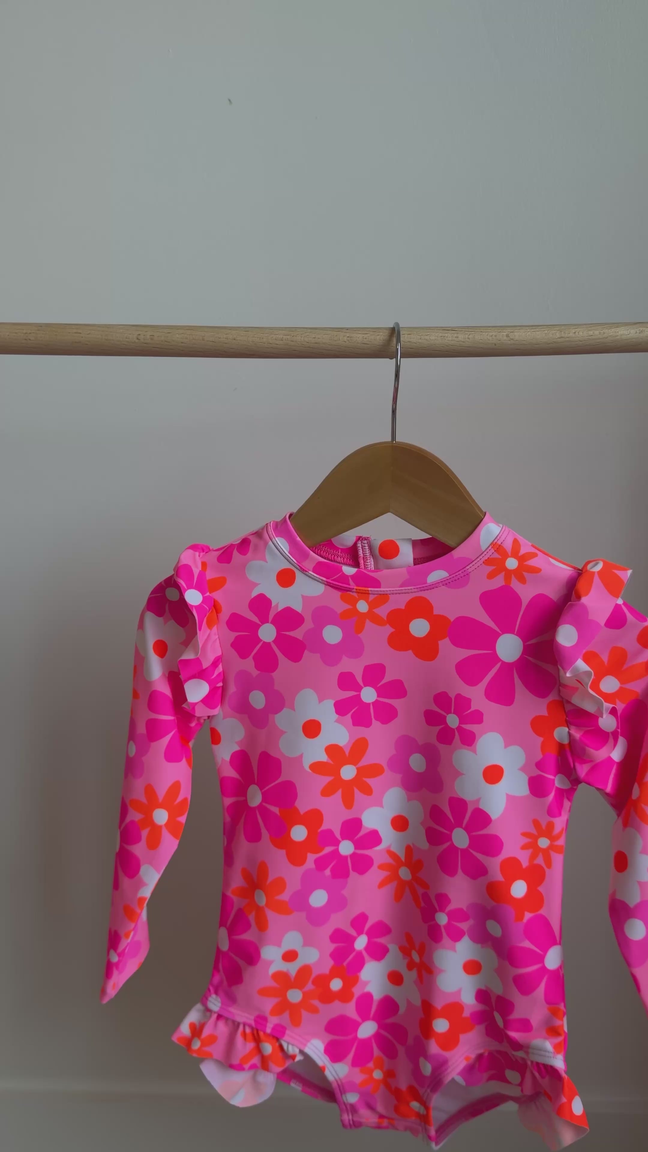 Pink floral one-piece swimsuit hanging on a rack