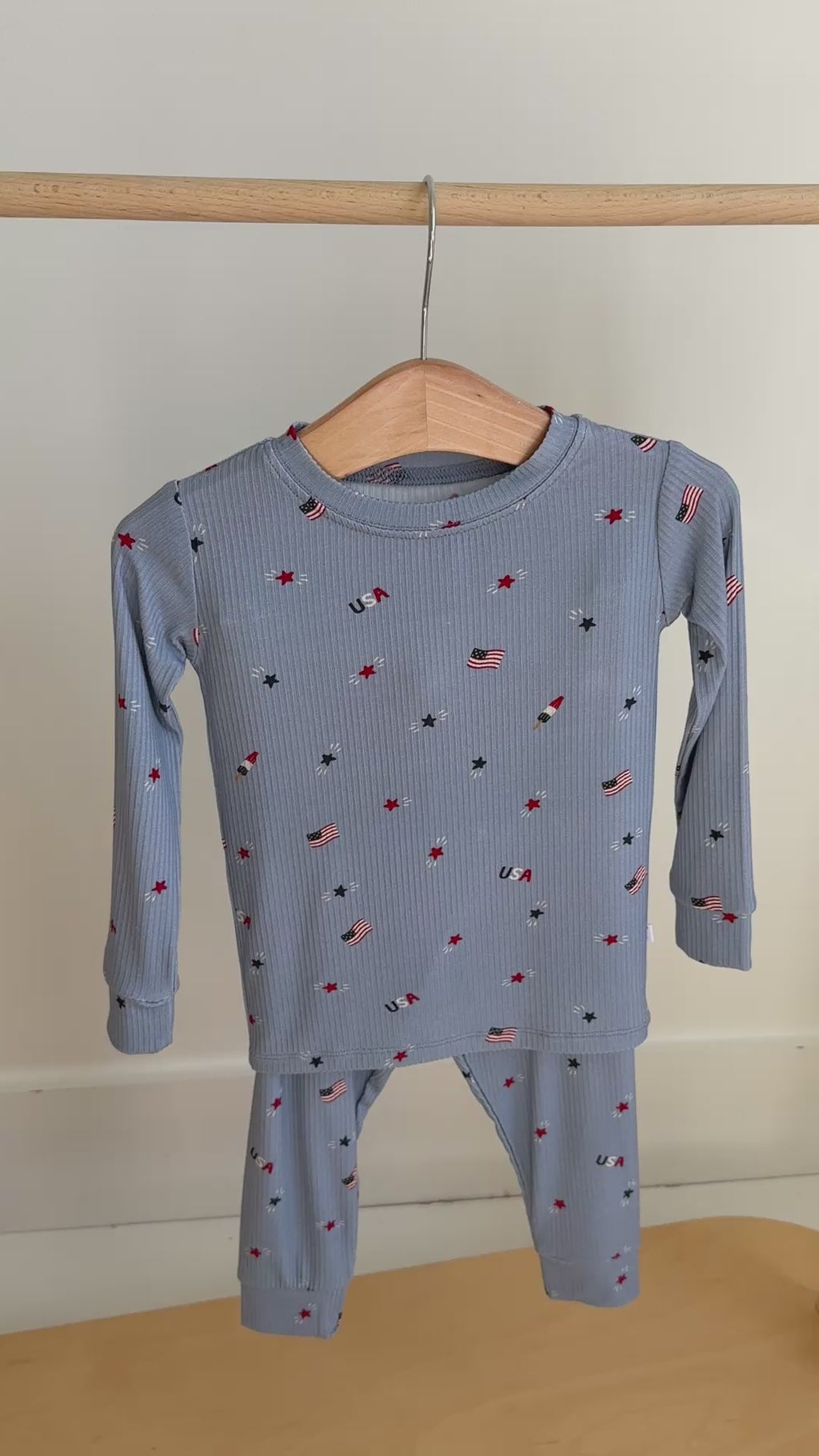 Children's pajama set with American flag pattern hanging on a rack