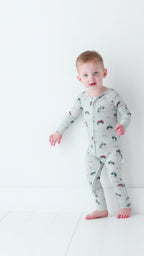 Child wearing a long-sleeve onesie with vehicle patterns on a white background