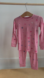 Video of a pink children's pajama set with a girly pattern hanging on a rack