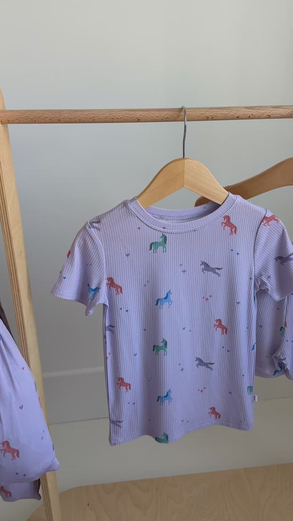 Children's pajama set with short-sleeve top and shorts, with unicorn design, hanging on a rack
