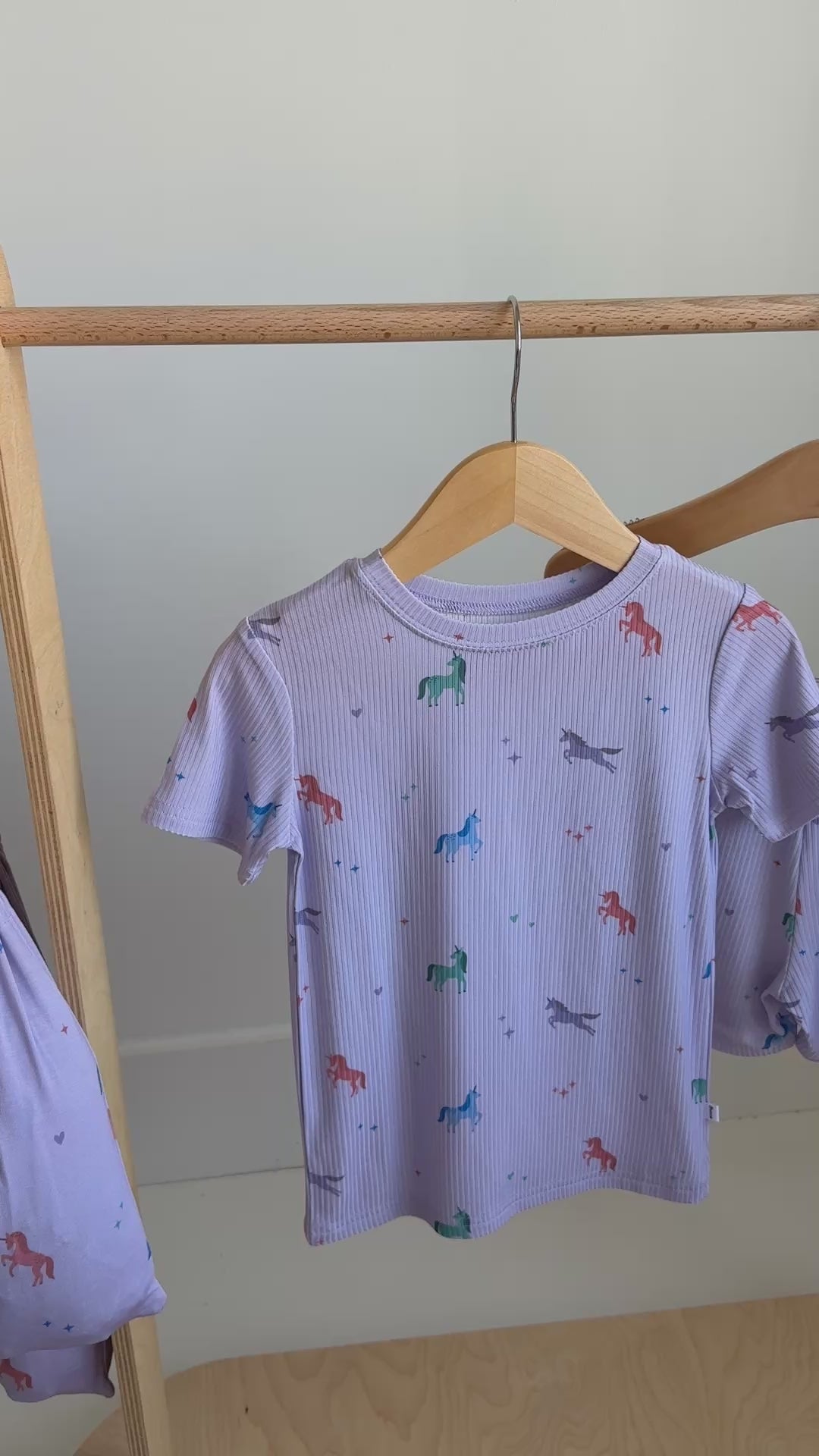 Children's pajama set with short-sleeve top and shorts, with unicorn design, hanging on a rack