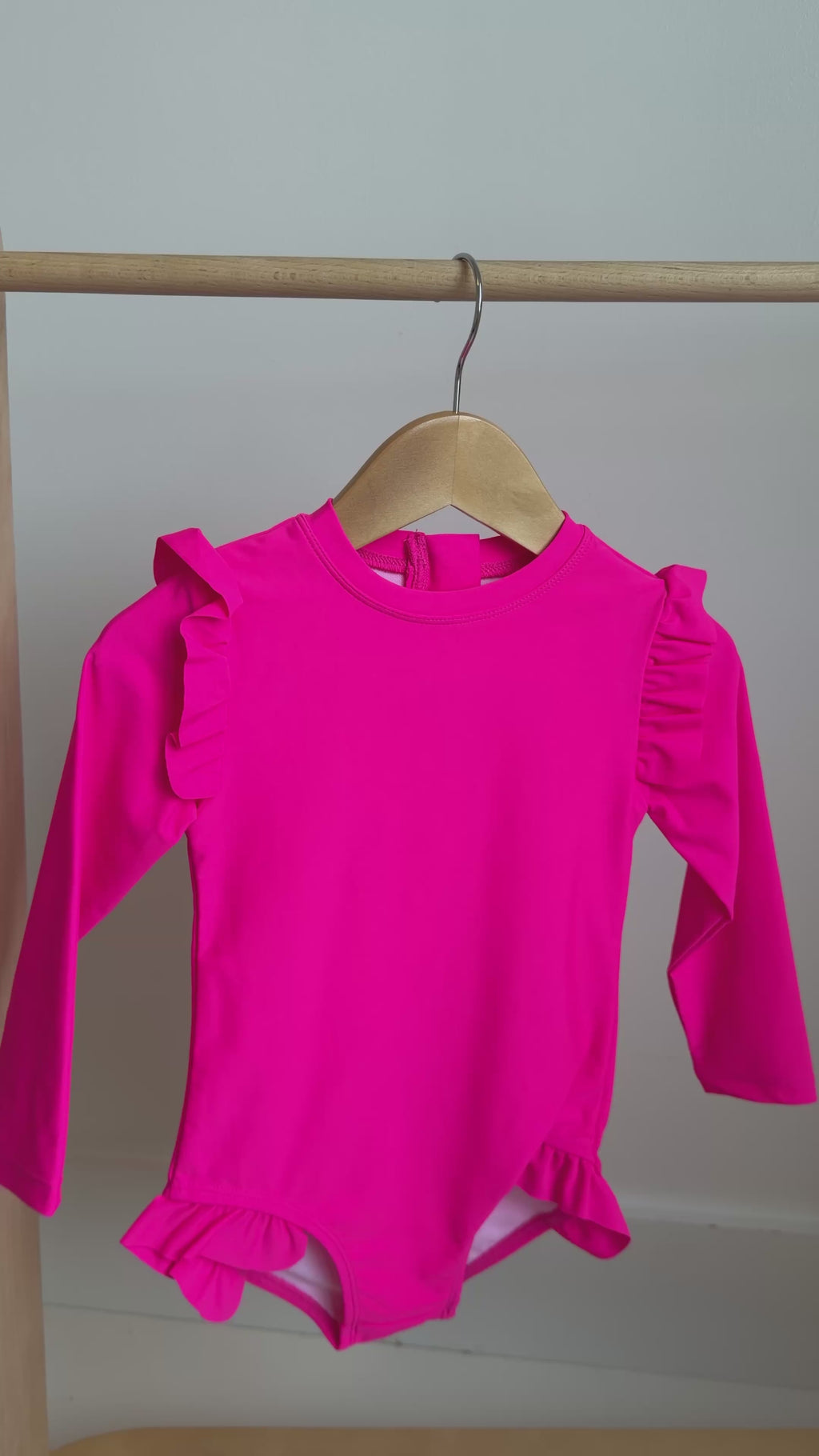 Bright pink one-piece swimsuit on a hanging rack