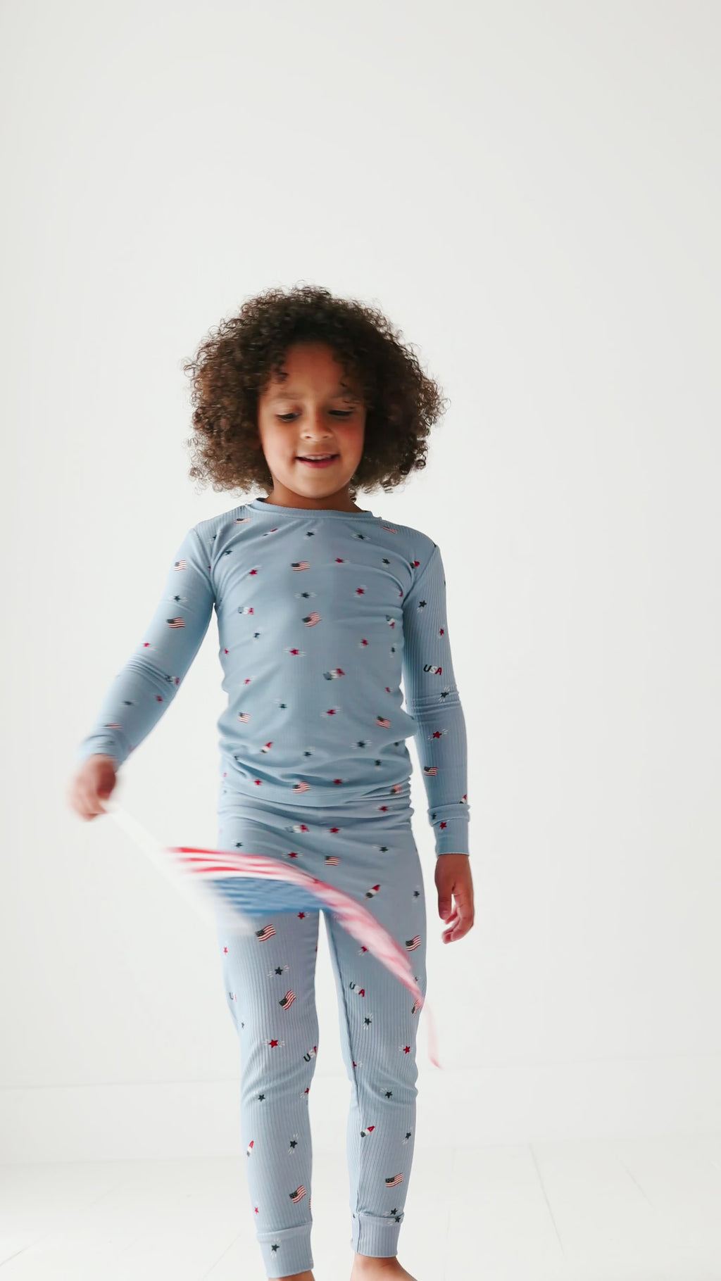 Child wearing a blue pajama set with stars and flag patterns on a white background