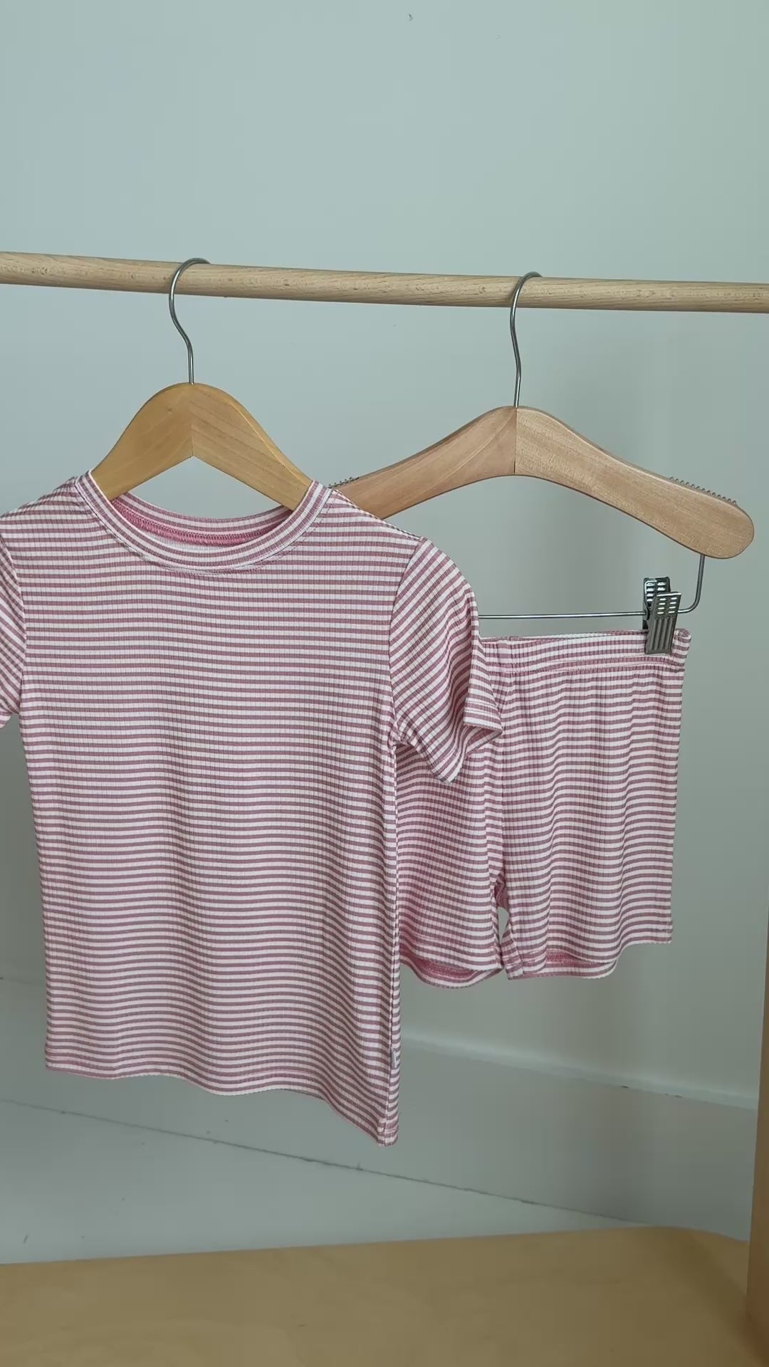 Pink striped shorts pajama set hanging on a rack