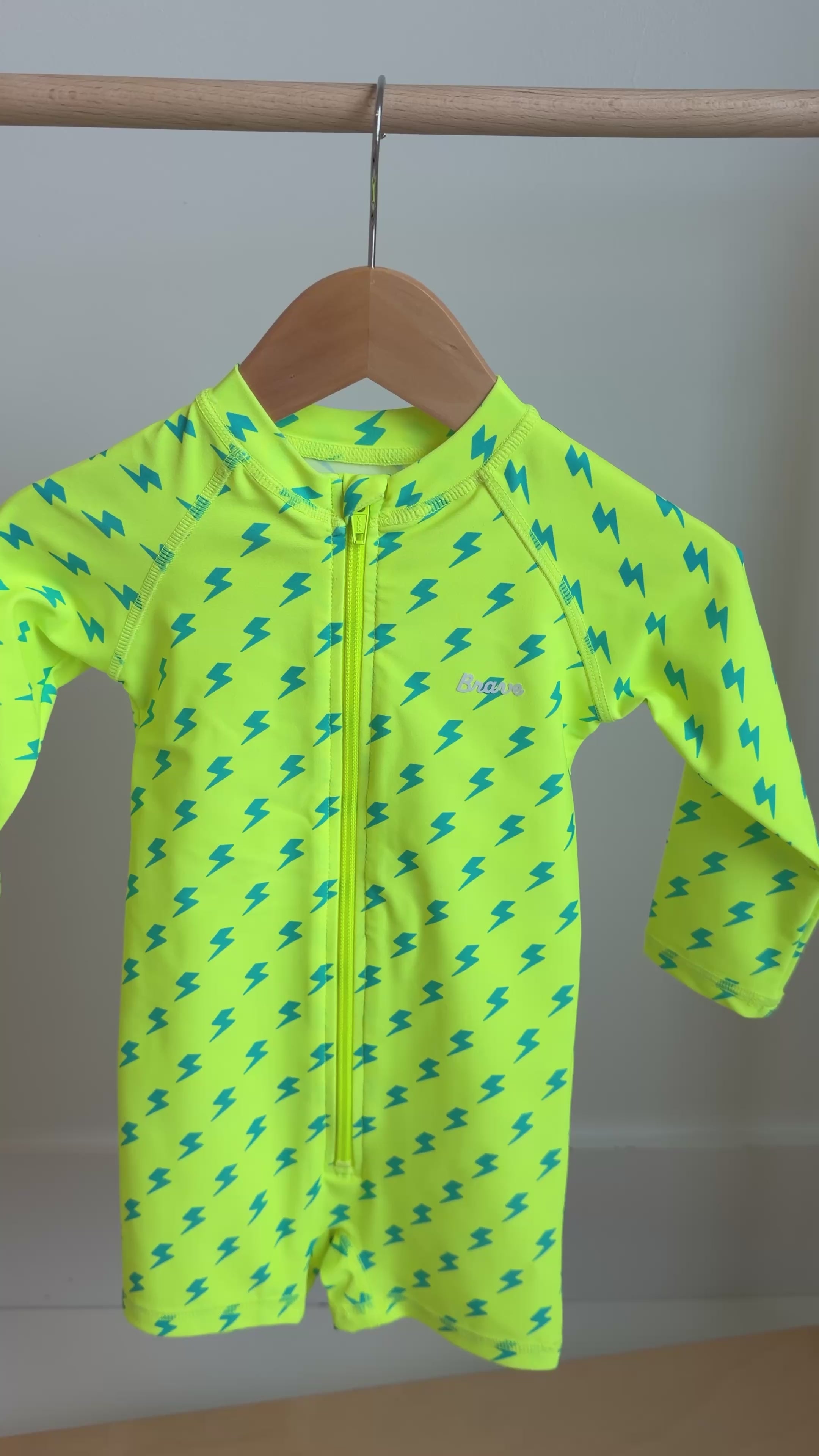 Yellow boy swimsuit with blue lightning bolt pattern hanging on a rack