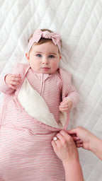 Baby wearing a pink and white striped outfit with a matching headband on a white background