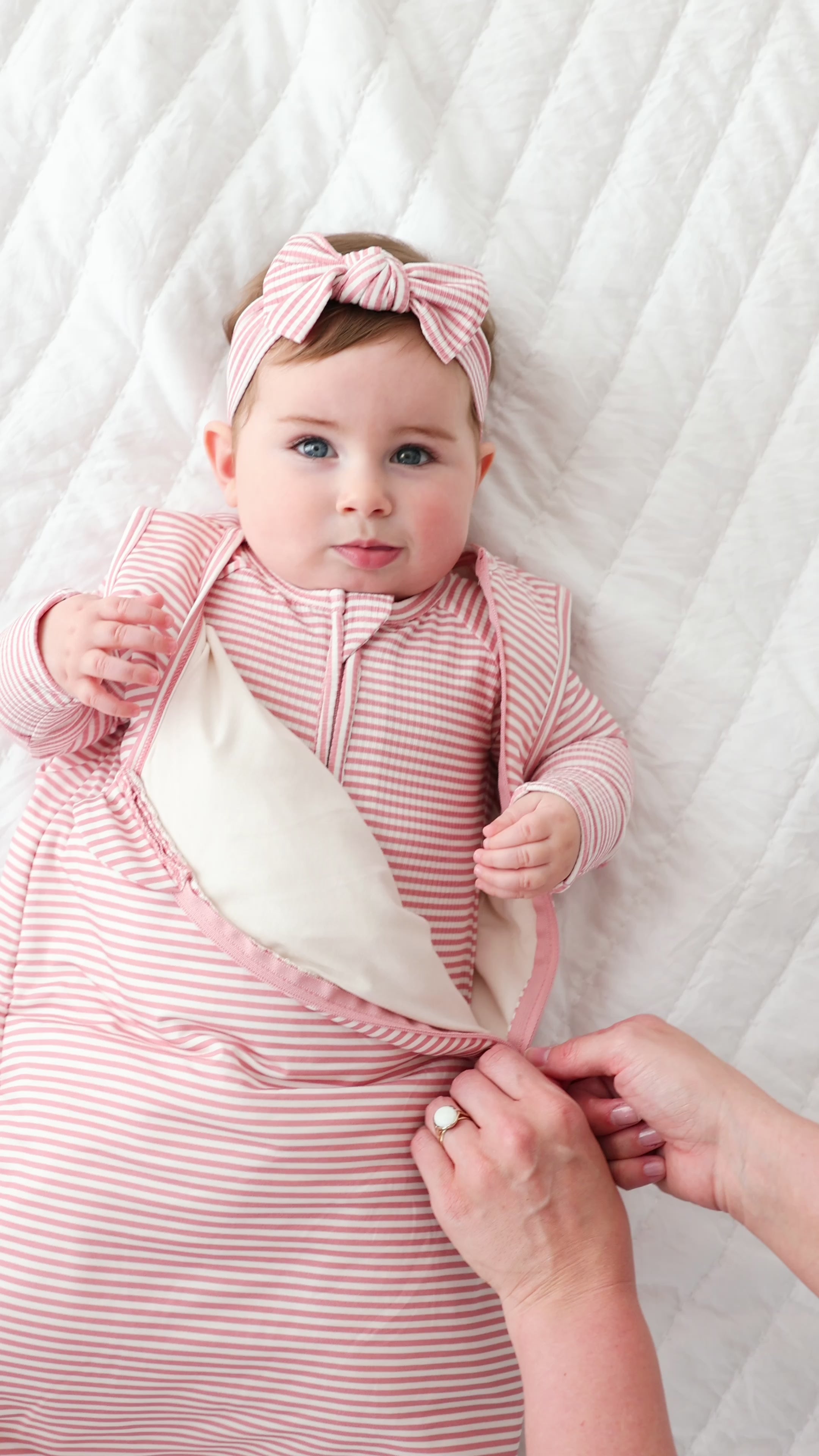 Baby wearing a pink and white striped outfit with a matching headband on a white background