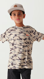 Child wearing a camouflage t-shirt, taupe cap and black shorts on a white background