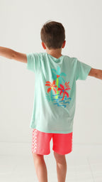 Child wearing a light blue t-shirt with colorful palm tree design on a white background