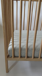 Video of a wooden crib with a gray mattress on a white background