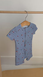 Baby romper with star and flag pattern hanging on a rack