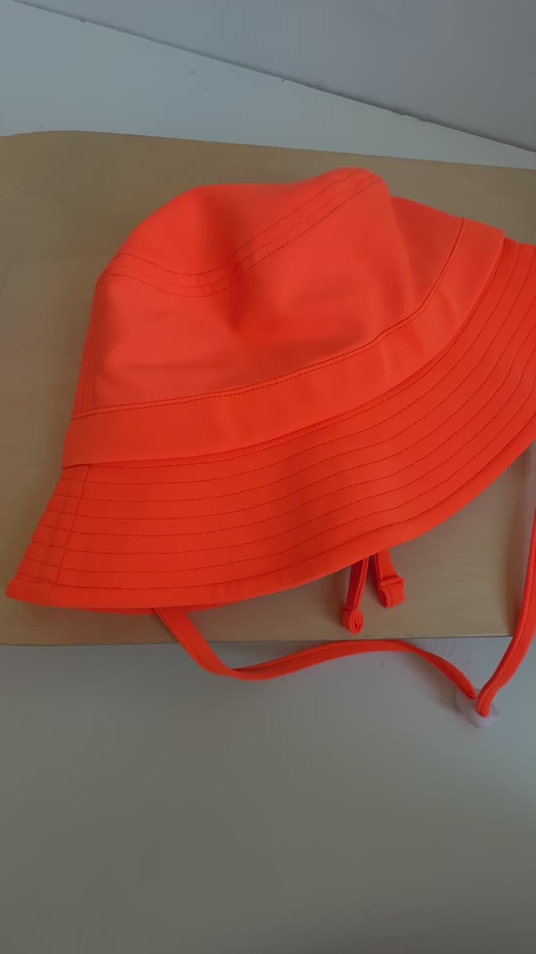 Orange bucket hat with a strap on a plain background
