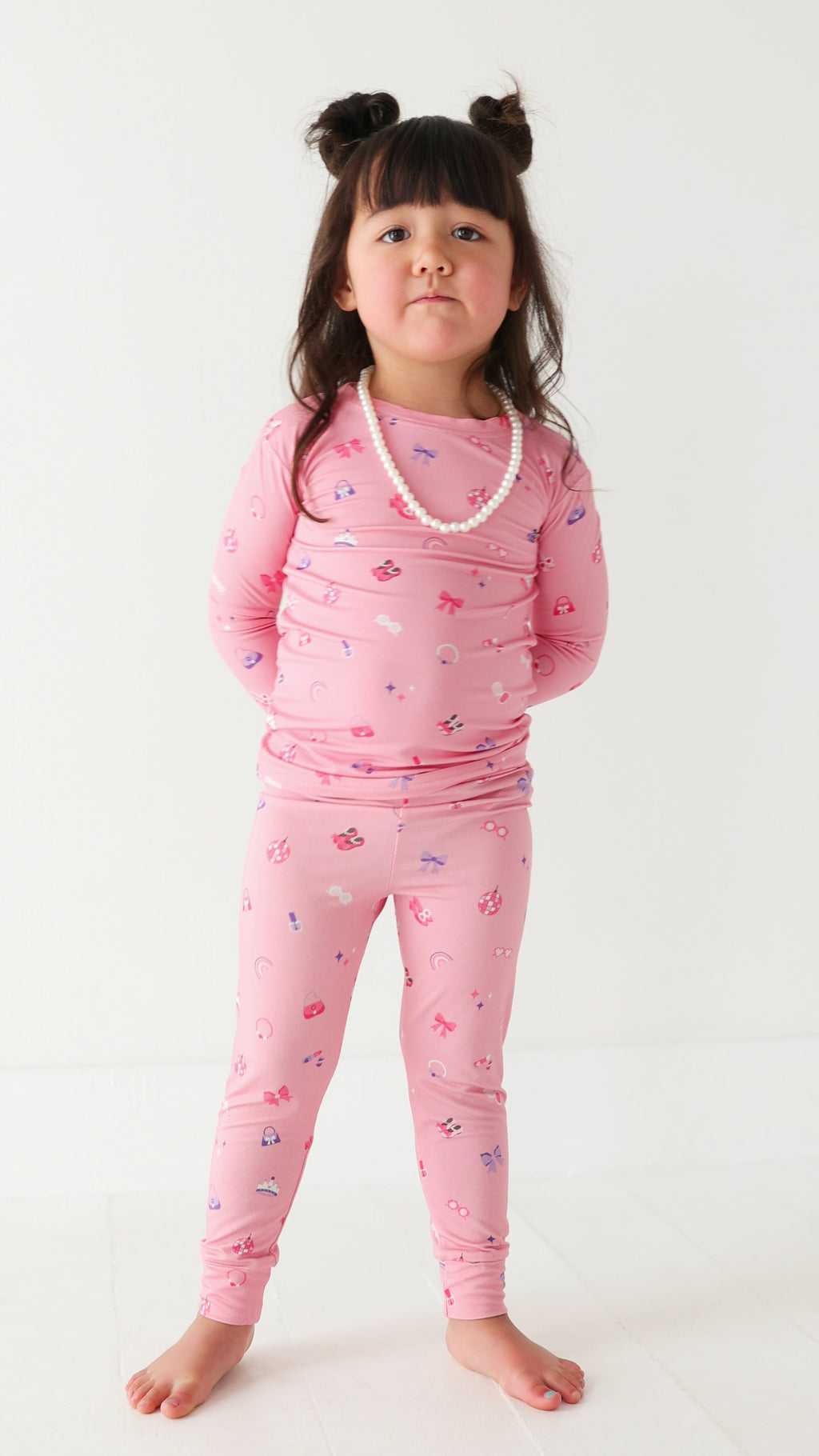 Video of a young girl wearing pink pajamas with girly patterns on a white background