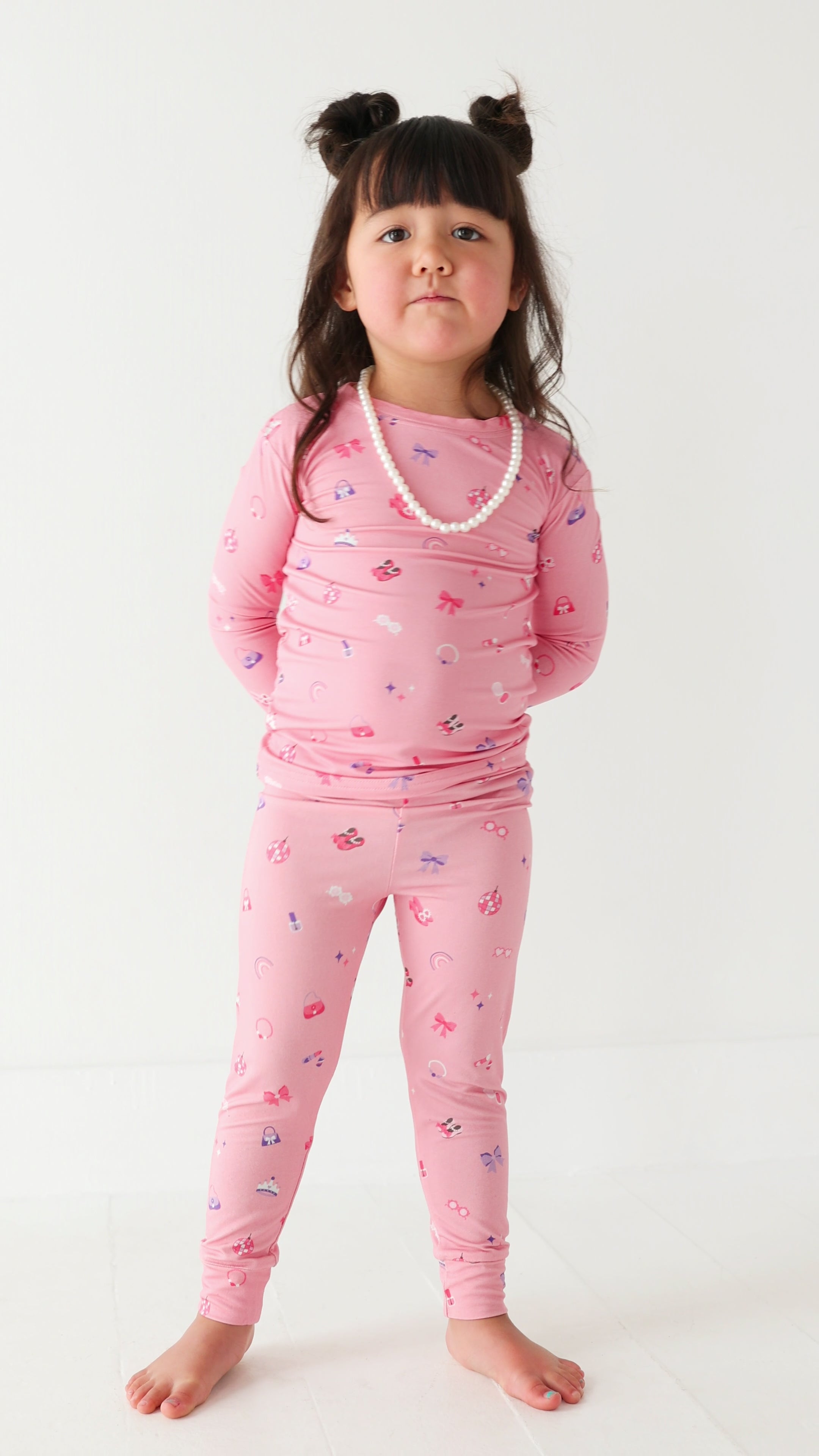 Video of a young girl wearing pink pajamas with girly patterns on a white background