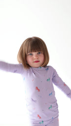 Video of a child wearing a purple pajama set with unicorn prints on a white background