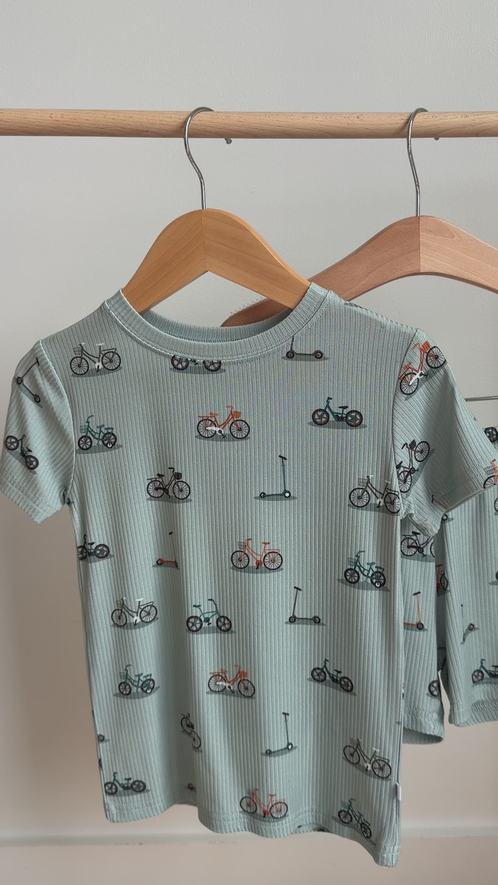 Video of a children's pajama shorts set with bike and scooter pattern hanging on a rack