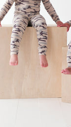 Video of two children wearing matching camouflage pajamas sitting on a white background
