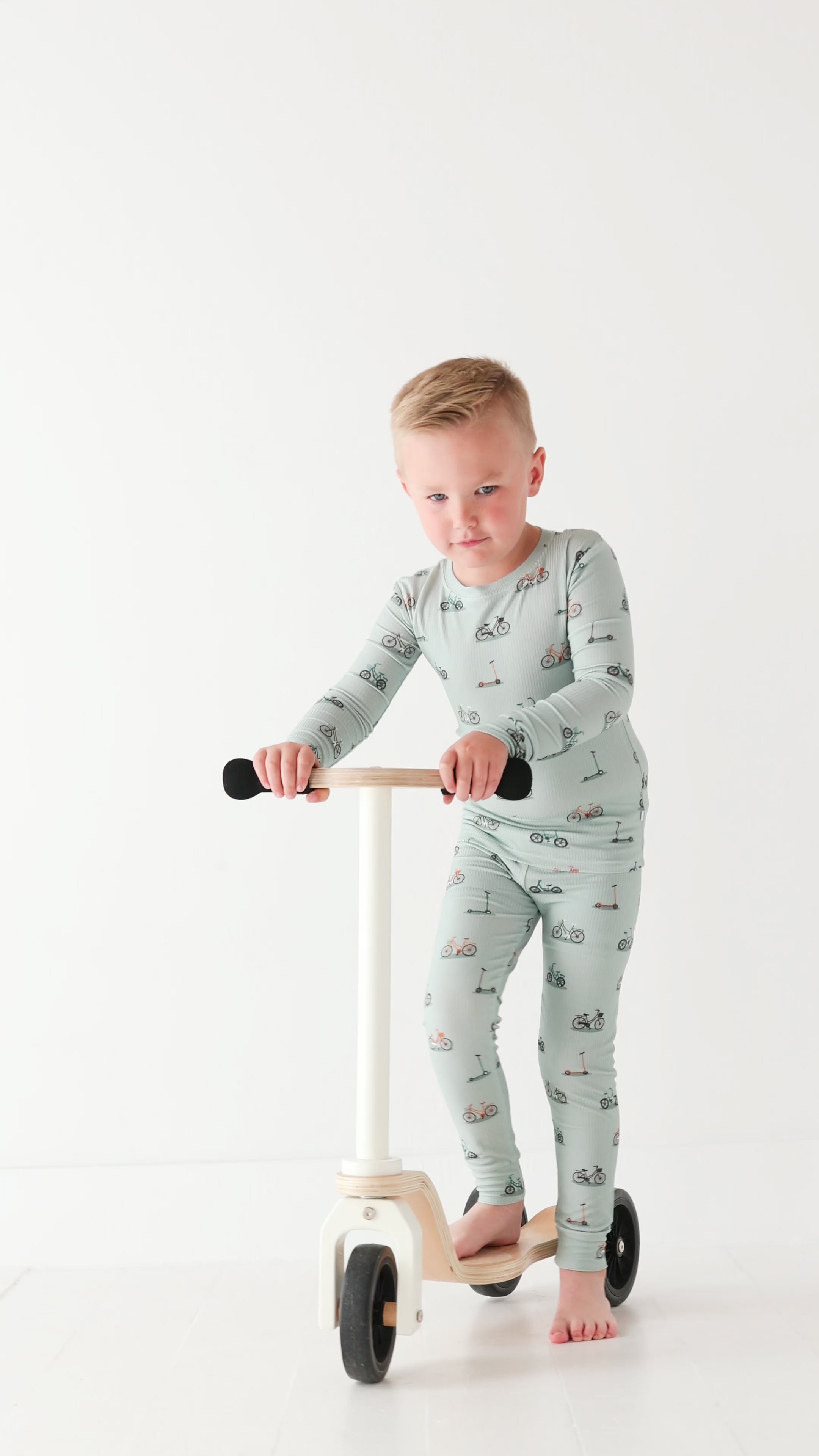 Video of a child wearing a pajama set holding a scooter on a white background
