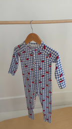 Video of a children's onesie with blue checkered pattern and red cherries hanging on a rack