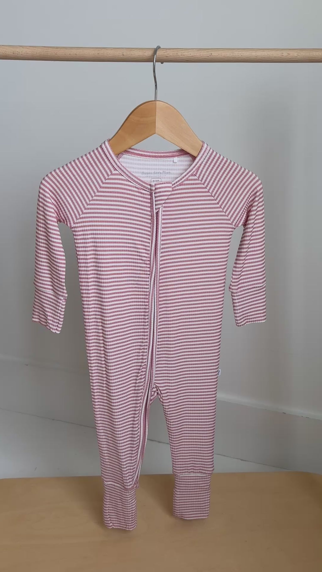 Pink striped onesie hanging on a rack