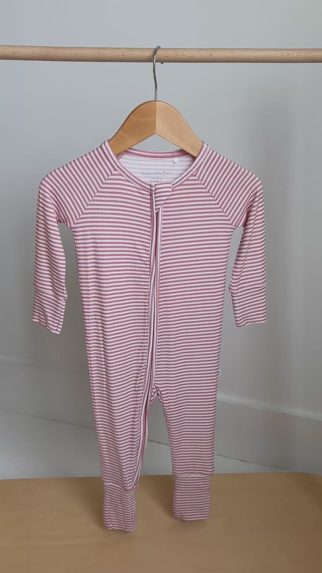 Pink striped onesie hanging on a rack