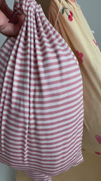 Pink striped sheets and fruity-patterned sheets in bags hanging on a rack