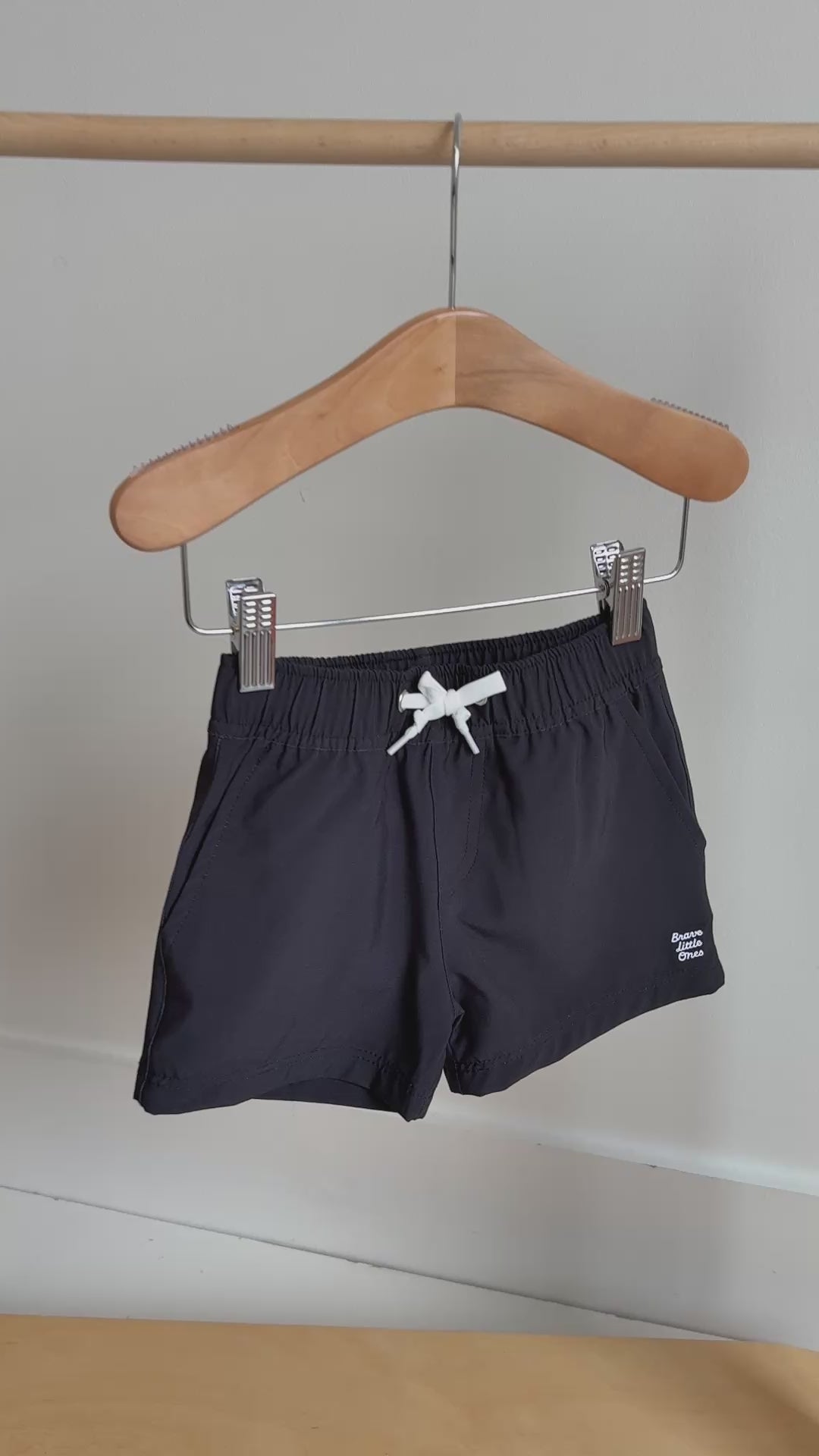 Black shorts with a white logo hanging on a rack