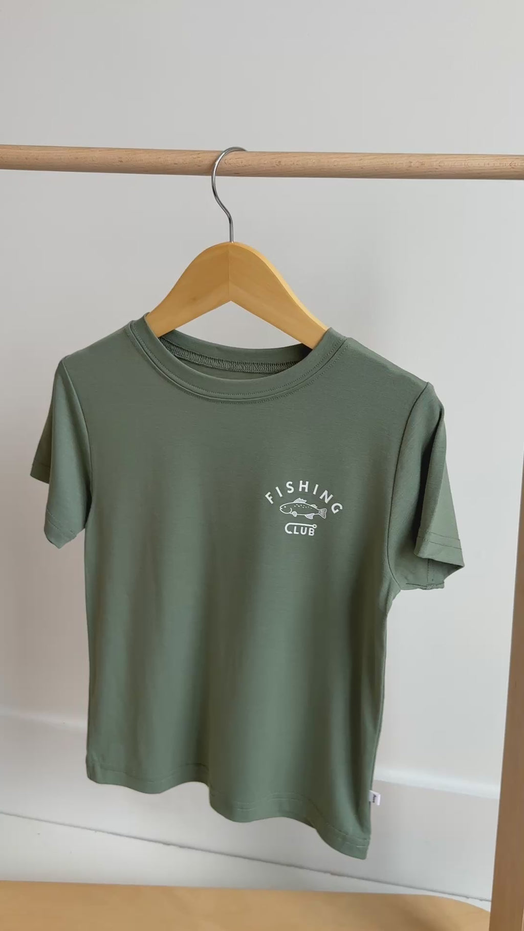 Green t-shirt with 'Fishing Club' text and logo hanging on a rack