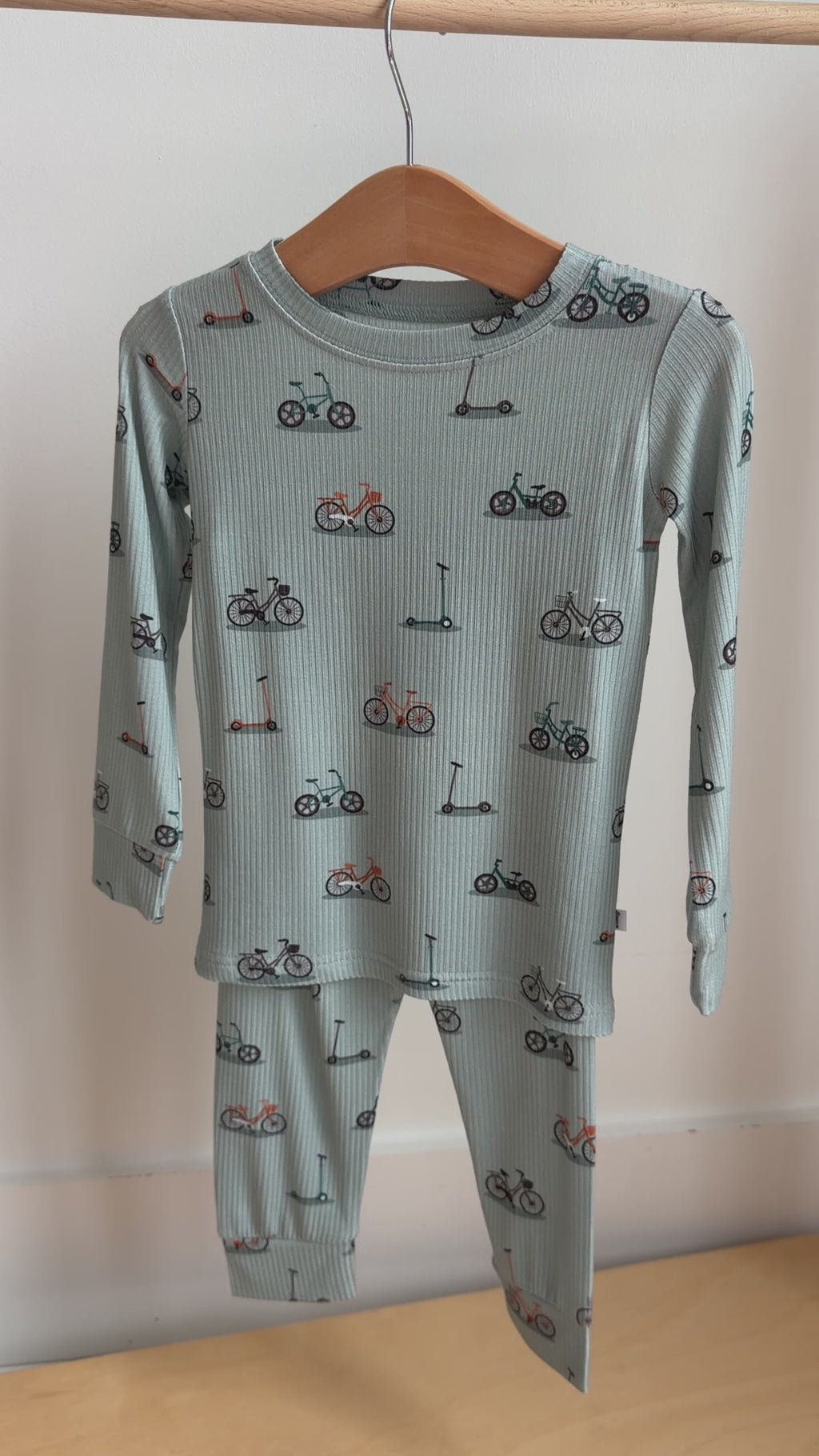 Video of a children's pajama set with bikes and scooter pattern hanging on a rack