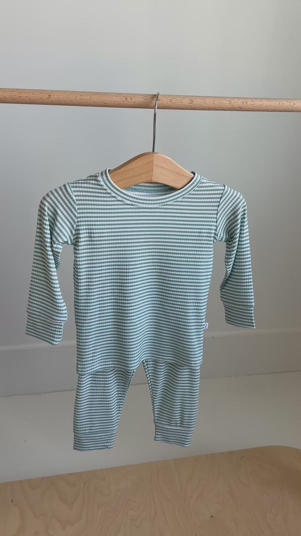 Video of a blue and white striped pajama set with top and pants hanging on a rack