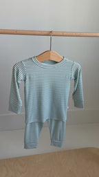 Video of a blue and white striped pajama set with top and pants hanging on a rack