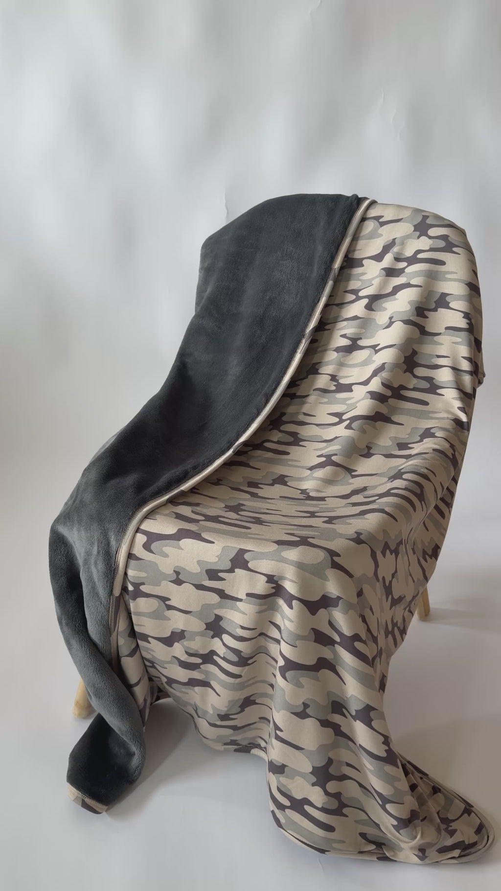 Video of a camouflage-patterned blanket with dark backing draped on a chair