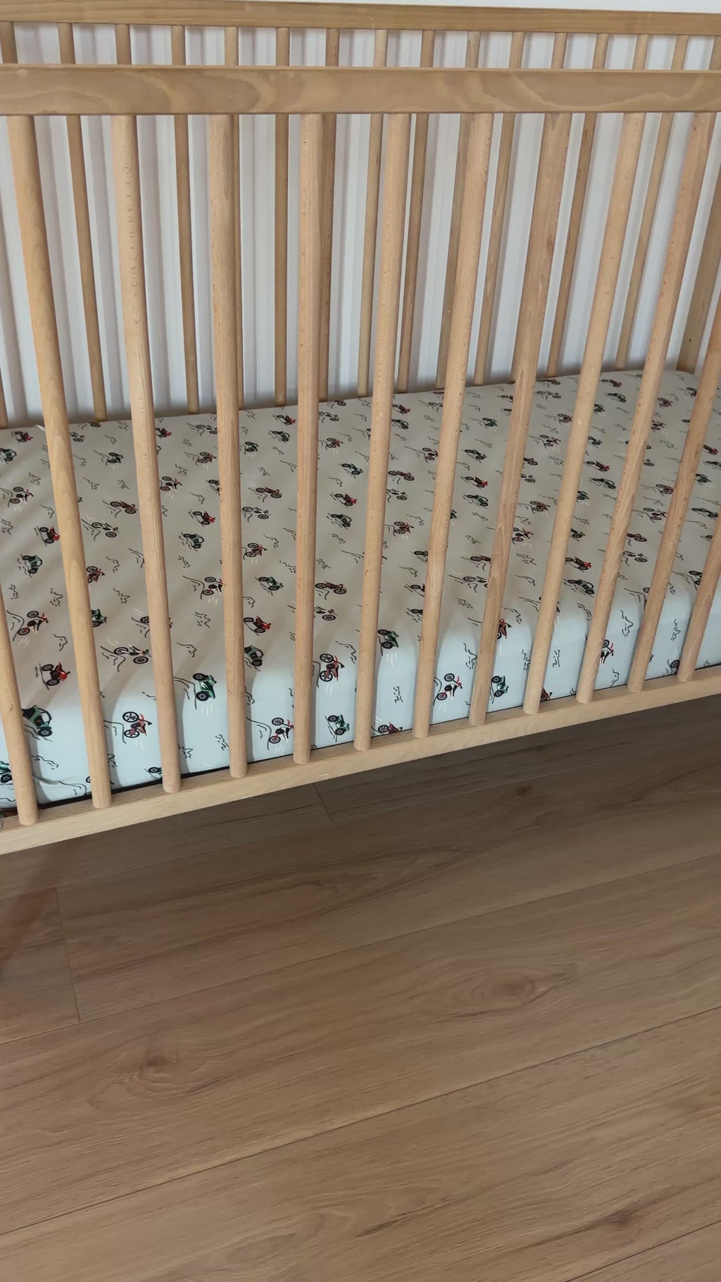 Fitted crib sheet with dirt bike pattern on a wooden crib with mattress