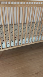 Fitted crib sheet with dirt bike pattern on a wooden crib with mattress