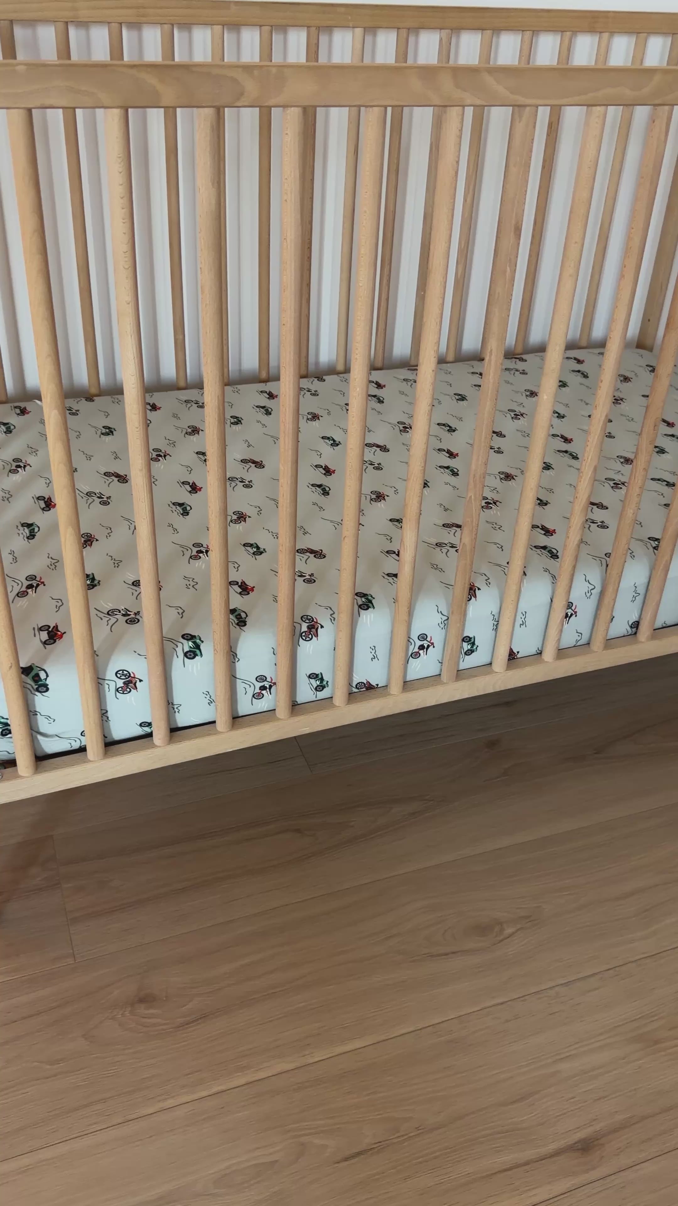 Fitted crib sheet with dirt bike pattern on a wooden crib with mattress