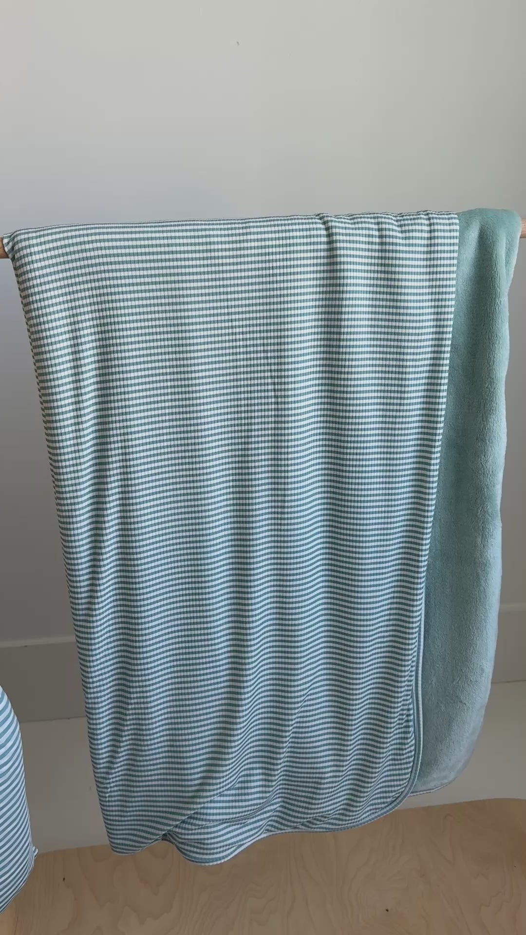 Light blue striped blanket draped over a wooden hanging rack