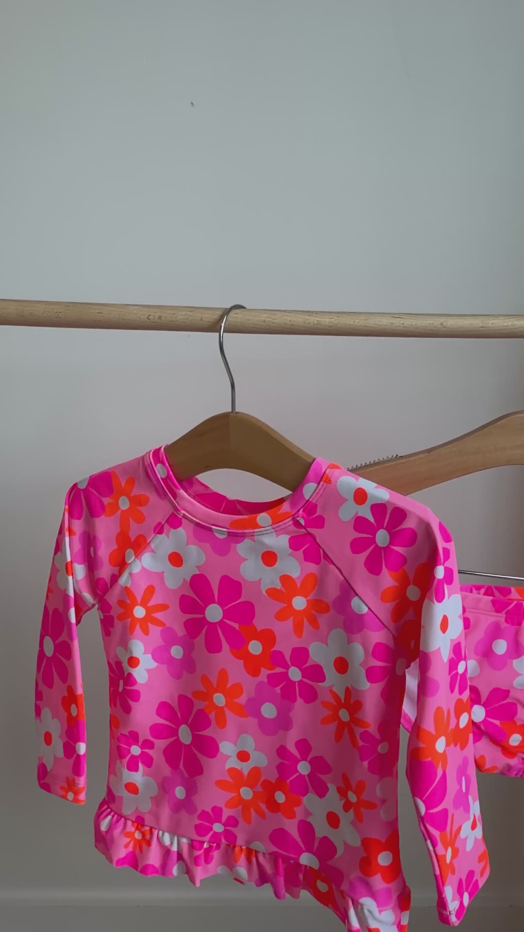 Pink floral two-piece swimsuit hanging on a rack