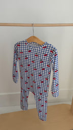 Children's pajama set with blue gingham pattern and red cherries hanging on a rack