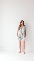 Woman wearing a light gray pajama set with vehicle patterns on a white background