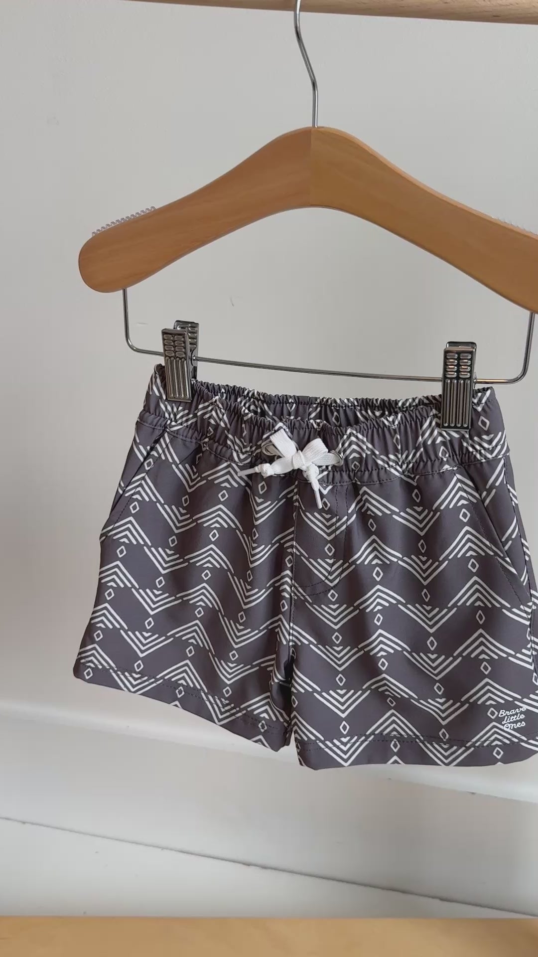 Gray shorts with geometric pattern hanging on a rack