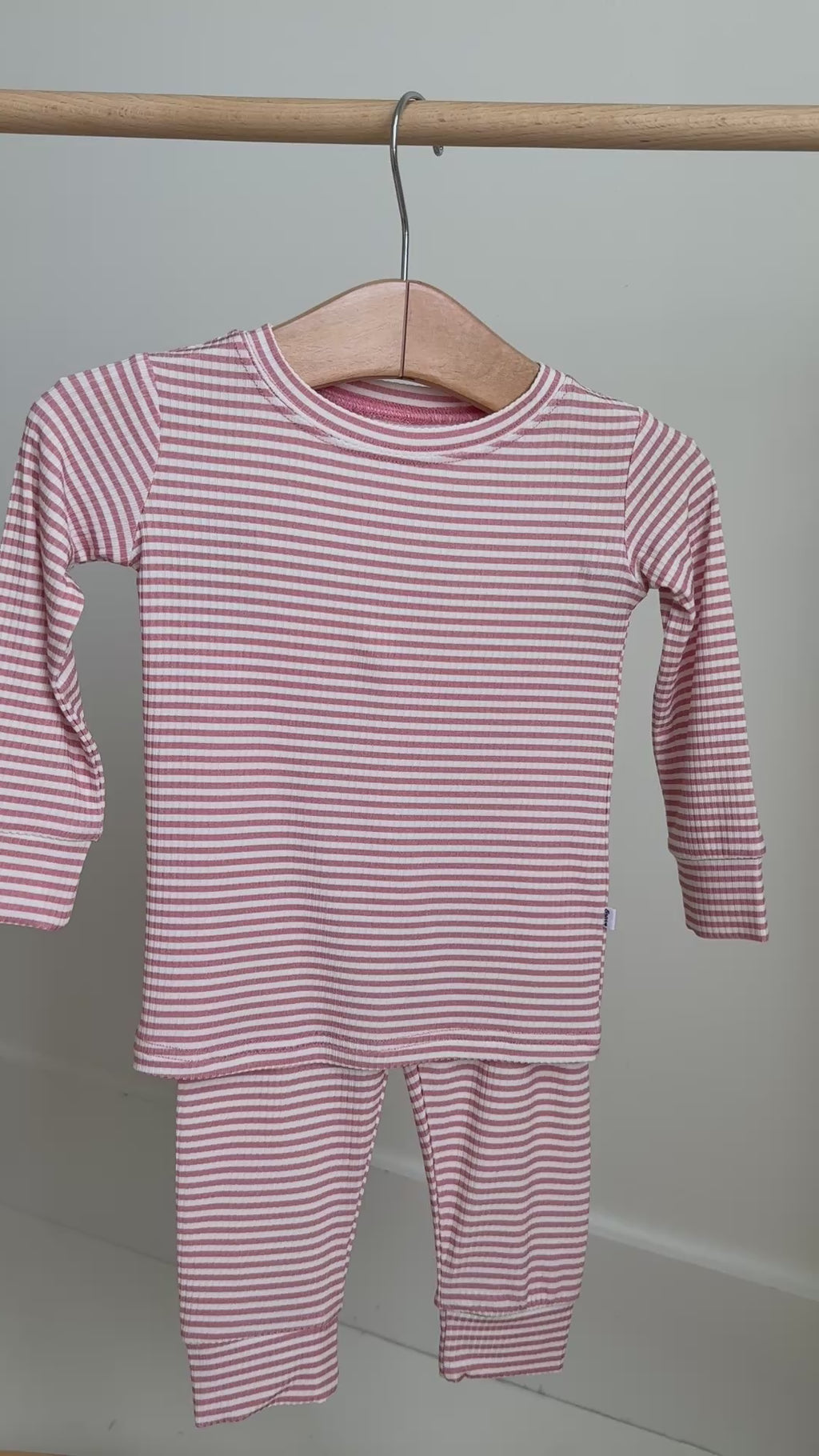 Pink striped long sleeve pajama set hanging on a rack
