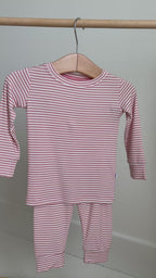 Pink striped long sleeve pajama set hanging on a rack