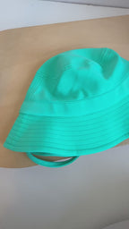 Turquoise bucket hat with a strap on a plain background