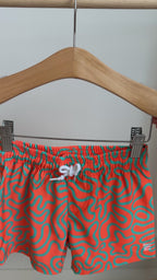 Orange and blue squiggly-patterned swim shorts hanging on a rack