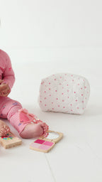 Video of a child in pink onesie playing with girly toys on a white background
