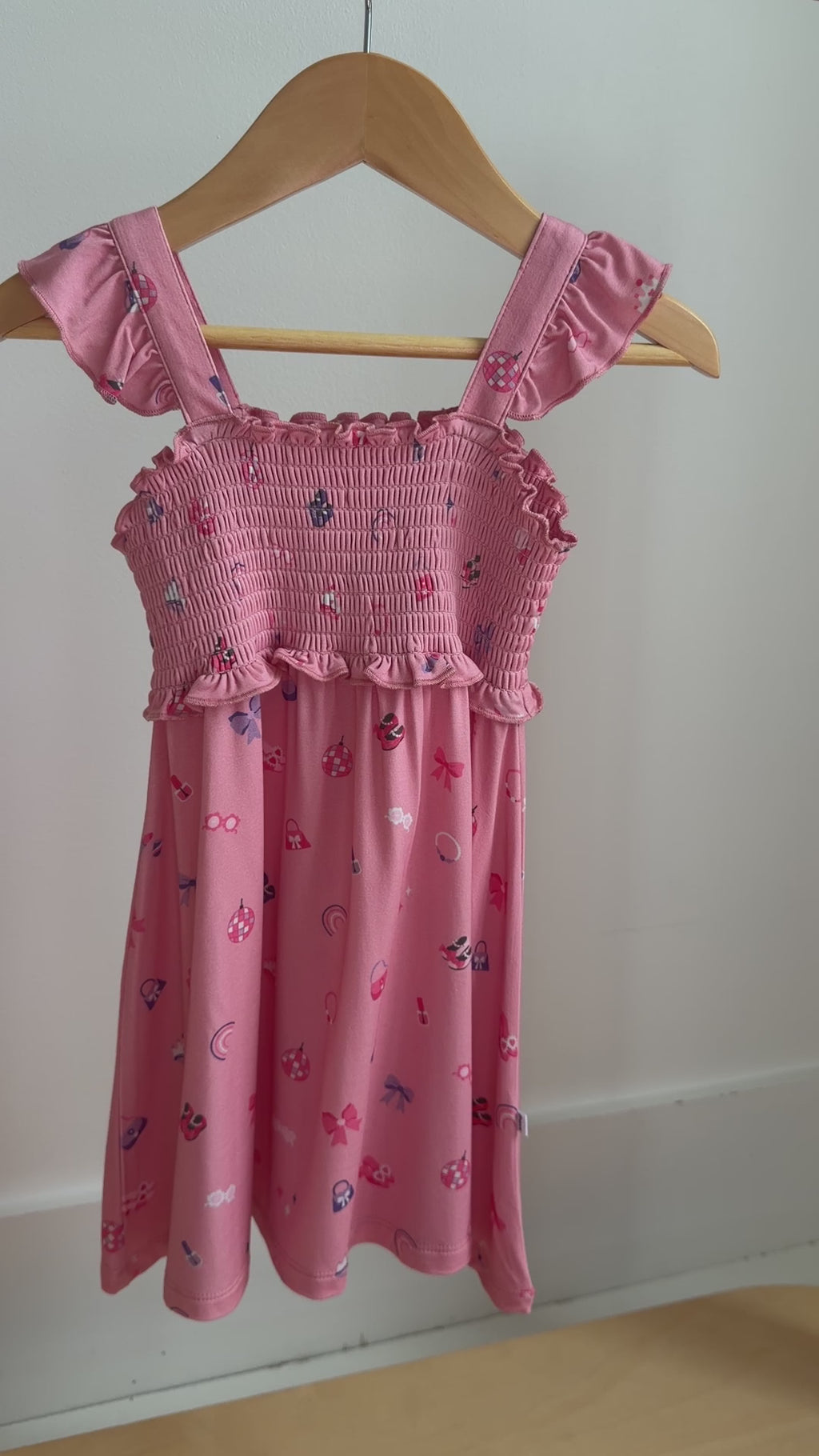 Video of a pink dress with girly patterns hanging on a rack