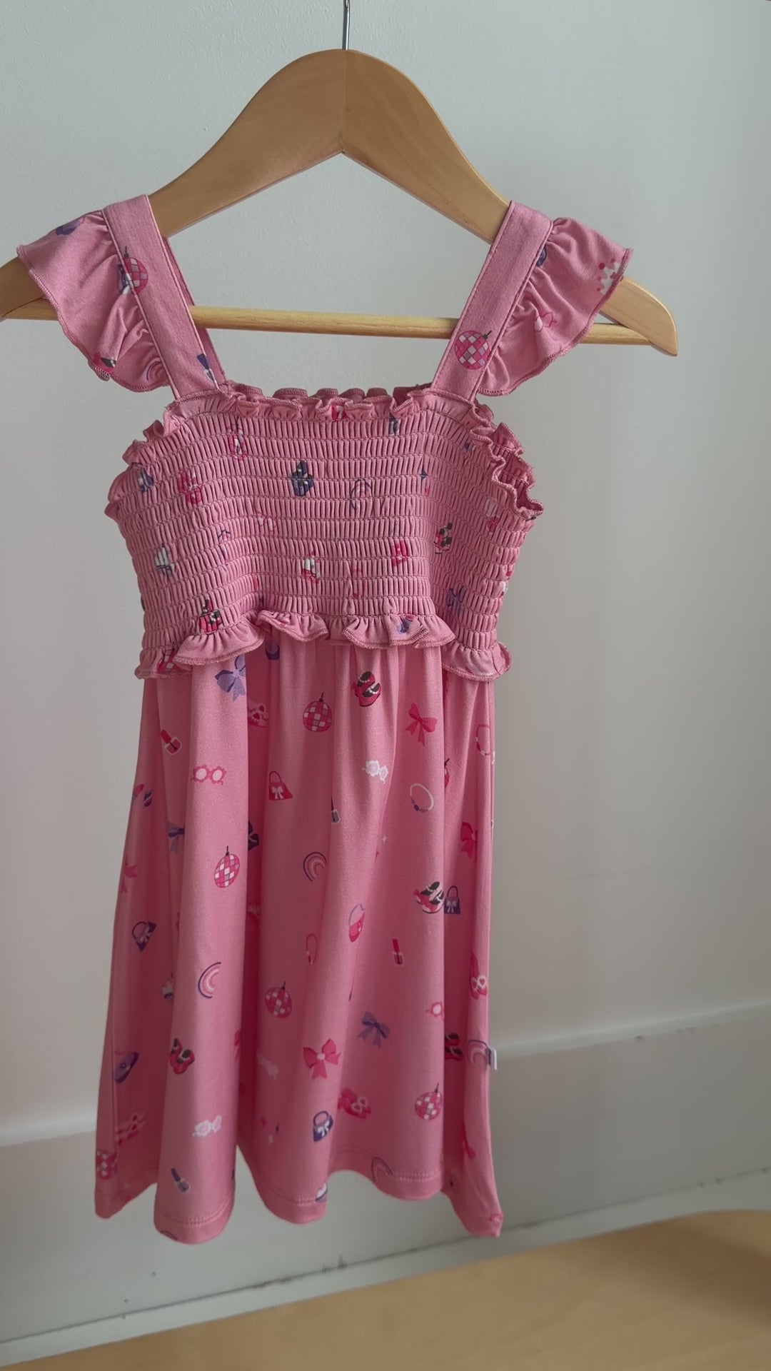 Video of a pink dress with girly patterns hanging on a rack