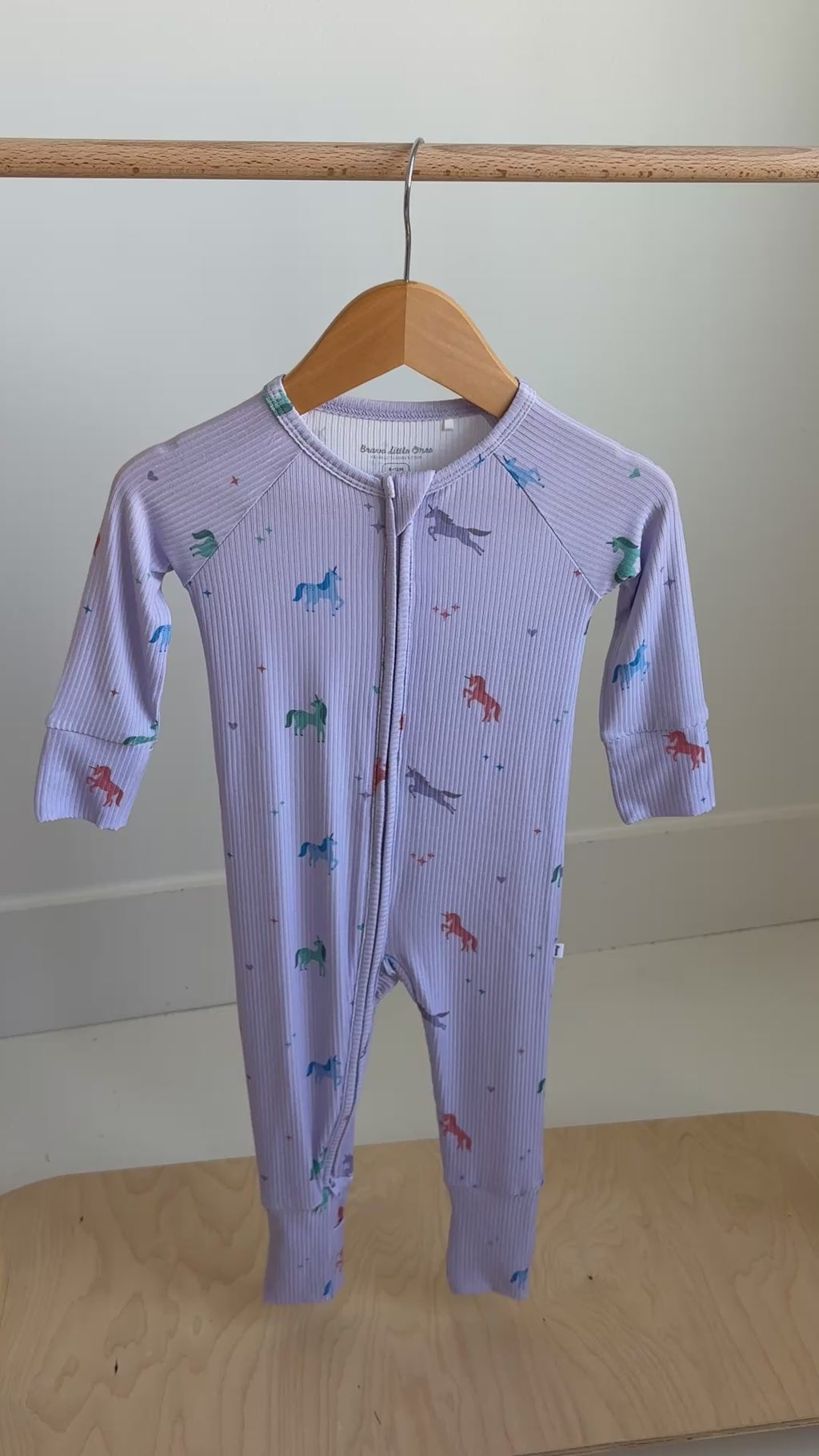 Video of a baby onesie with unicorn patterns hanging on a rack