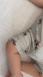 Baby wearing a light gray onesie with vehicle patterns while sleeping